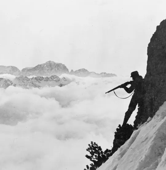 An Austro-Hungarian mountain soldier taking aim with his rifle from a mountain slope.