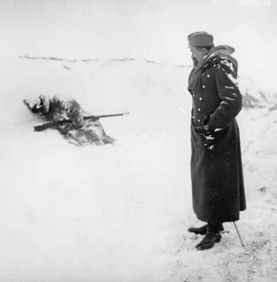 A Serbian officer looking at a dead Serbian soldier, frozen on the side of the road, during the retreat to the Adriatic Coast, December 1915.